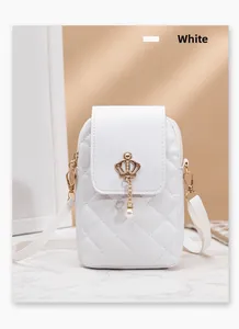Close-up of white quilted phone bag with gold crown charm and pearl pendant detail