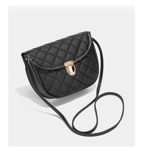 Détail d'un sac besace noir matelassé avec fermoir doré rotatif et texture en similicuir