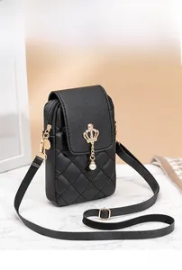 Detail of black quilted phone bag featuring a gold crown charm and pearl pendant