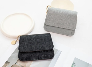 Detailed macro view of lychee-patterned coin purses in black and gray with gold hardware