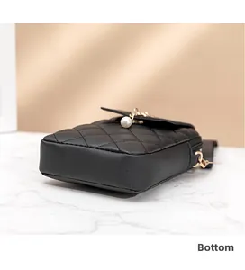 Detail view of the black quilted phone bag base with pearl charm and gold hardware