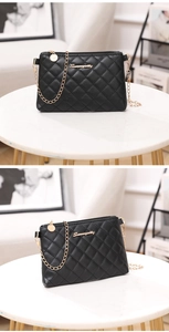 Detail of black quilted crossbody bag with gold chain strap and metallic brand logo
