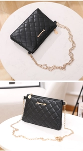 Detailed view of black quilted crossbody bag with golden logo and chain strap