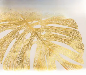 Detailed close-up of golden monstera leaf foil stamping on a white cushion cover