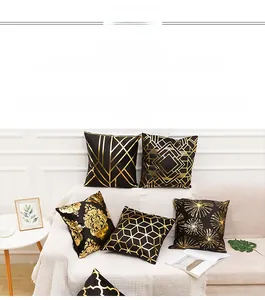 Detail of assorted black and gold throw pillow covers arranged on a cozy modern sofa