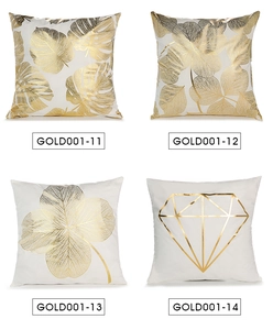 Detail view of four square white pillow covers with gold leaf and geometric patterns