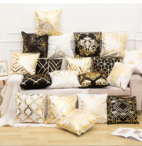 Detail of luxury gold foil pillow covers with geometric and leaf patterns on a sofa