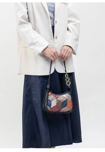 Close-up of quilted patchwork shoulder bag with gold chain strap and metal logo