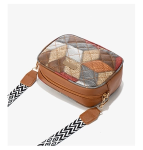Close-up of color-block crossbody bag featuring quilted patterns and wide fabric strap