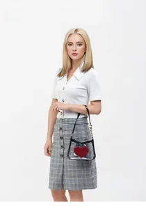 Transparent PVC crossbody bag with red heart patch on a female model with gold chain