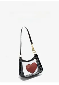 Detail of transparent PVC crossbody bag with a large red heart and black patent trim