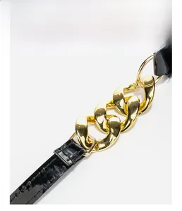 Detail of black patent leather strap with gold thick chain and double stitching craft