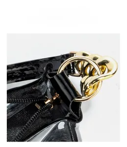 Detail of high-gloss black patent leather bag with gold circular metal rings and zipper