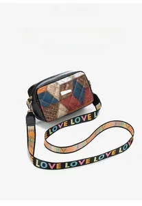 Close-up of small crossbody bag showing printed shoulder strap and textured panel