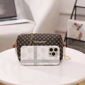 Sac à bandoulière monogramme avec logo doré sur table en marbre à côté d'un smartphone