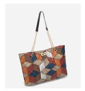 Detail of multi-textured patchwork tote with crocodile pattern and golden turn-lock