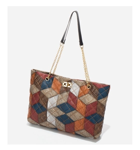 Detail of multi-color patchwork tote bag with crocodile texture and gold metal twist lock