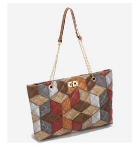 Detail of multi-color patchwork tote bag featuring crocodile texture and gold turn-lock