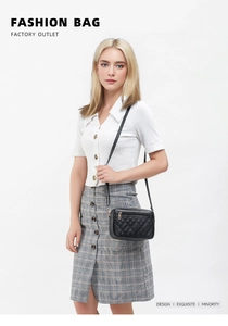 Detail shot of black quilted shoulder bag with gold zipper and minimalist leather strap