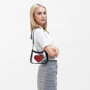 Transparent PVC crossbody bag with black trim and red heart logo shown on model