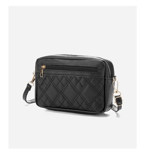 Detail of black quilted shoulder bag featuring gold-tone zippers and textured faux leather