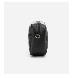 Close-up of black quilted shoulder bag featuring gold D-ring hardware and zipper