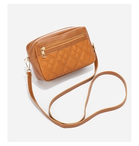 Detailed view of caramel brown quilted crossbody bag with golden metal hardware details