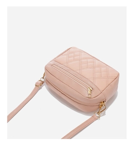 Detailed macro view of quilted beige shoulder bag with double zippers and gold hardware