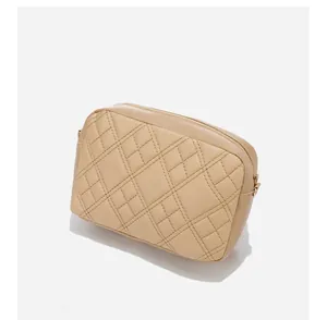 Detail view of beige quilted handbag featuring classic diamond stitching and gold-tone zipper