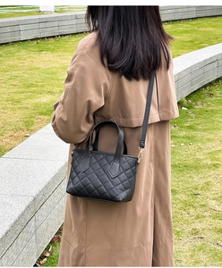 Dettaglio mini borsa a secchiello nera trapuntata con finiture dorate indossata all'aperto
