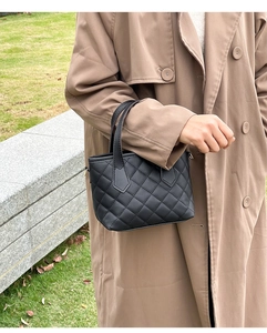 Borsa a secchiello trapuntata nero opaco portata da modella in un contesto esterno