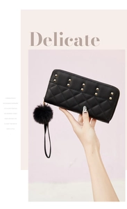 Detail of black faux leather wallet with quilted pattern, gold studs and pompom charm