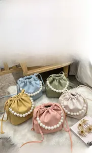 Detail of drawstring bucket bags with pearl handles in five pastel colors on white faux fur