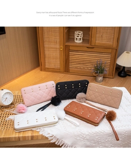 Five assorted colors of quilted leather purses with studs and plush pom-poms on a wooden table