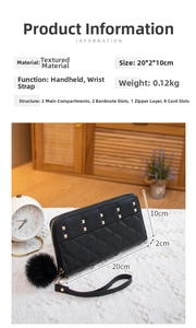 Close-up of black quilted wallet with gold studs, wristlet and plush pompom charm