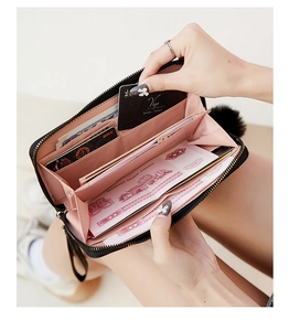 Detail of black long wallet with pink interior compartments and pompom zipper pull