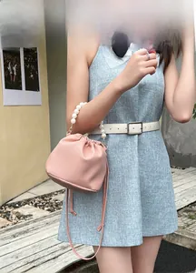Detailed view of pink lychee texture bucket bag with white pearl handle on a model