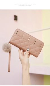 Detail of light pink quilted leather wallet featuring gold studs and a fur pom pom charm