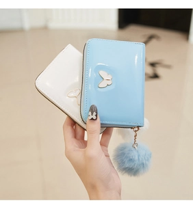 Détail du portefeuille en cuir avec boucle papillon et grand porte-clé pompon en peluche