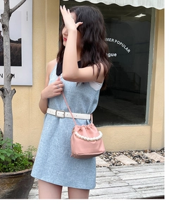Detail of pink drawstring bucket bag with litchi texture and elegant pearl handle