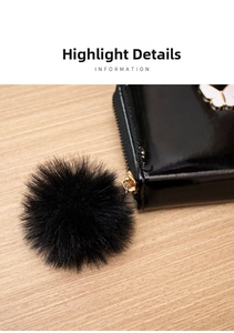 Détail d'un mini portefeuille en cuir verni noir avec zip doré et pompon en fausse fourrure