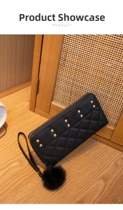 Detail of black quilted leather wallet with gold studs and decorative pompom charm