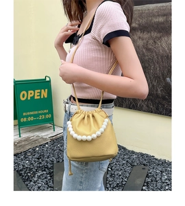 Detail of yellow lychee texture bucket bag featuring white pearl handle and drawstring