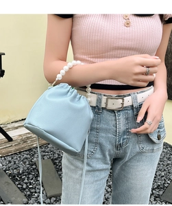 Close-up of light blue drawstring bucket bag with pearl handle on model's shoulder