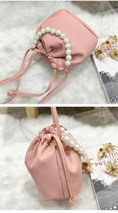 Detail view of a pink lychee grain bucket bag with a pearl handle and drawstring closure
