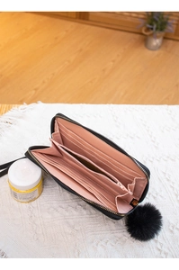 Internal view of black zip-around wallet with pink lining, card slots and fur ball charm