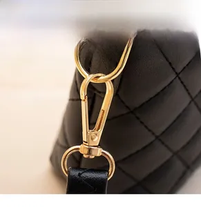 Detail of gold detachable metal hook on a black quilted leather bag with elegant finish