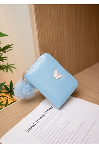 Détail du portefeuille en cuir PU bleu clair avec ornement papillon et grand pompon