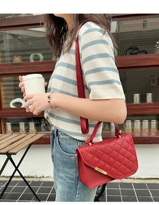 Detailansicht der roten gesteppten Handtasche mit goldener Metallschiene und breitem Gurt