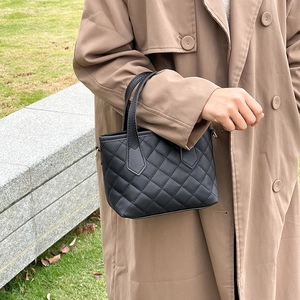 Elegante borsa a secchiello trapuntata nera con manici mostrata in un contesto all'aperto